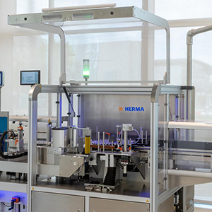 Automatische Etikettiermaschine von HERMA mit verschiedenen Komponenten zur Etikettierung und Verpackung.