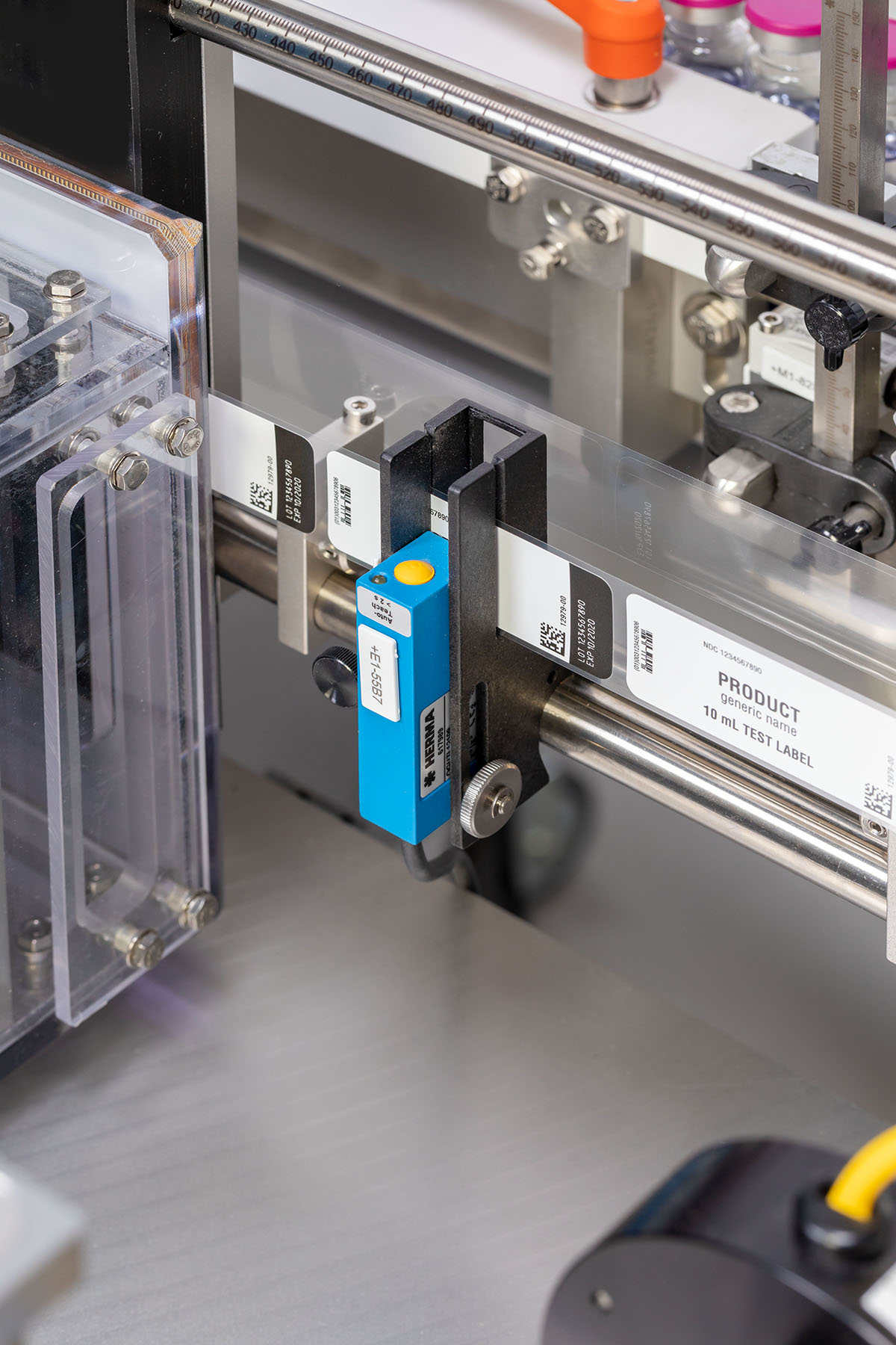 Ein Etikettiergerät mit einem blauen Sensor, der Etiketten auf transparenten Verpackungen erkennt. Mehrere Etiketten sind sichtbar.