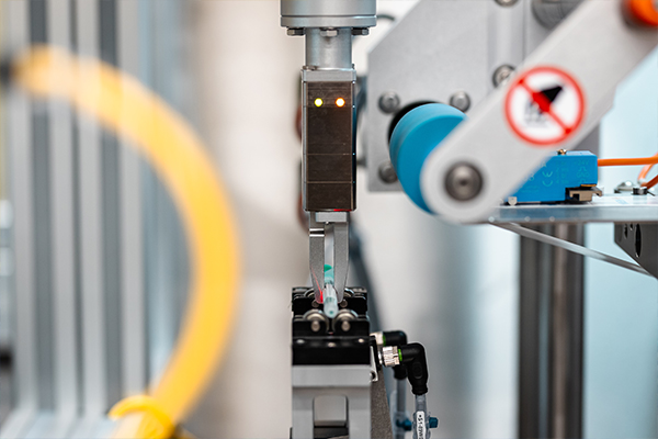 Ein automatisierter Roboterarm mit einem Greifer, der eine präzise Bewegung ausführt, um ein Objekt zu erfassen.