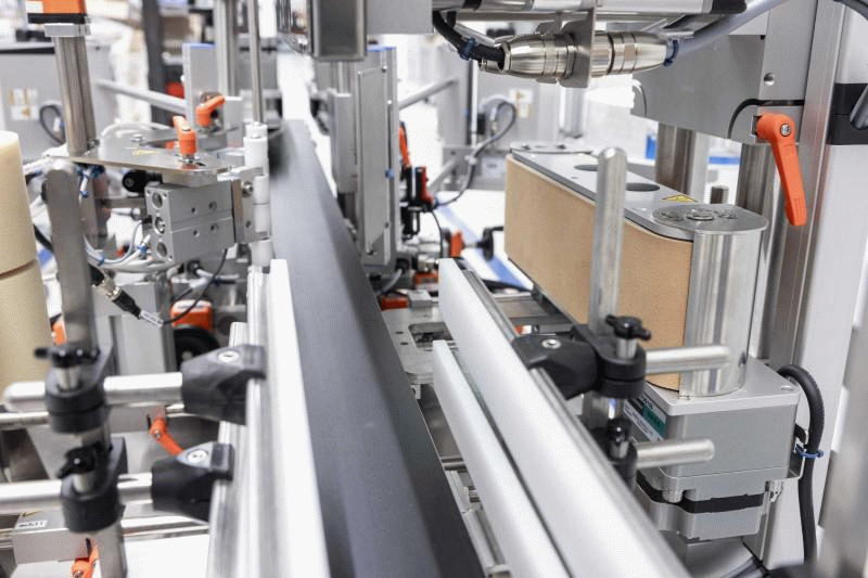 Automatisierte Maschinen zur Verpackung, mit Förderbändern und verschiedenen mechanischen Komponenten zur Handhabung von Produkten.