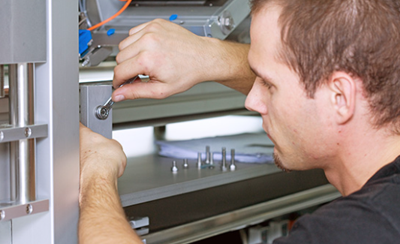 Ein Techniker arbeitet mit einem Schraubenschlüssel an einer Maschinenkomponente, um sie zu montieren oder zu reparieren.