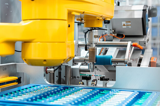 工业机器人有两种不同的型号，一个放在桌子上，另一个在装配单元上，周围环绕着技术图形。